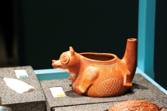 A museum volunteer shows a decorative pot used for frothing cocoa. The Mayans blew into the tail to create froth.