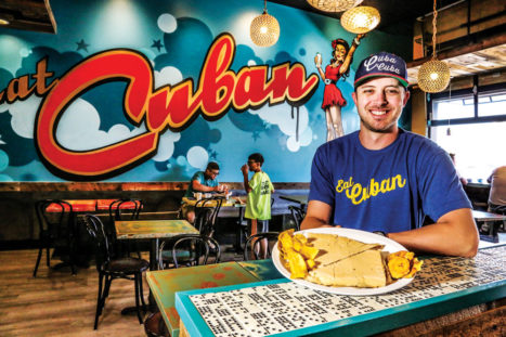 General Manager Josh Ranson enjoys his favorite meal - a Cubano with tostones and plantain chips. Dominoes built into the bar reflect the popularity of the game in Cuba.