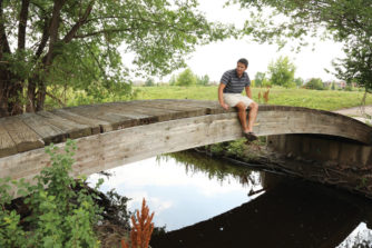 Loren Ting, a partner in the development of Stanley Marketplace, sits on a bridge over Westerly Creek where it flows by Stanley.