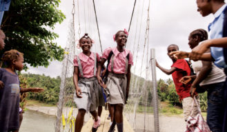 School children who previously had to walk through the river to get to school, happily cross the bridge. 