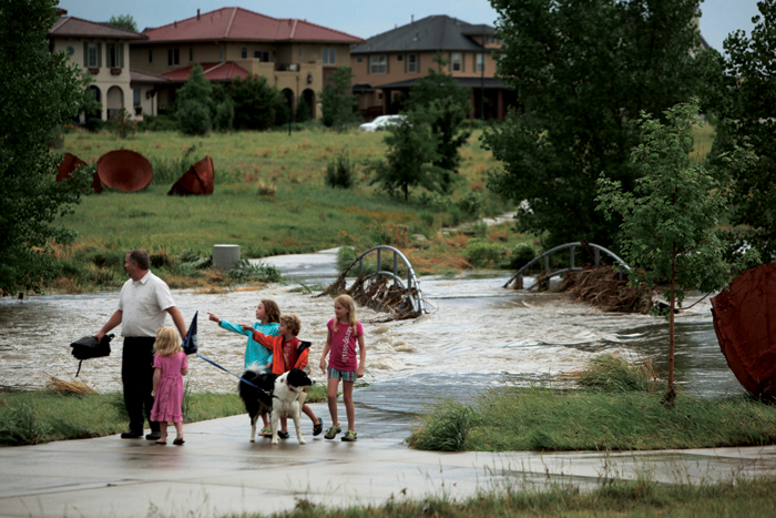 A family walks by Westerly Creek after the flood
