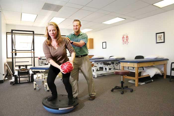 Alex Lanton, owner of the new Atlas Physical Therapy practice on Quebec St., demonstrates a balance platform with the help of office coordinator Kristin Dohrn.