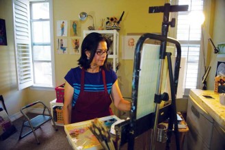 Artist Paula Arroyo-Natan, Ed’s wife, works on a painting in their home studio. 