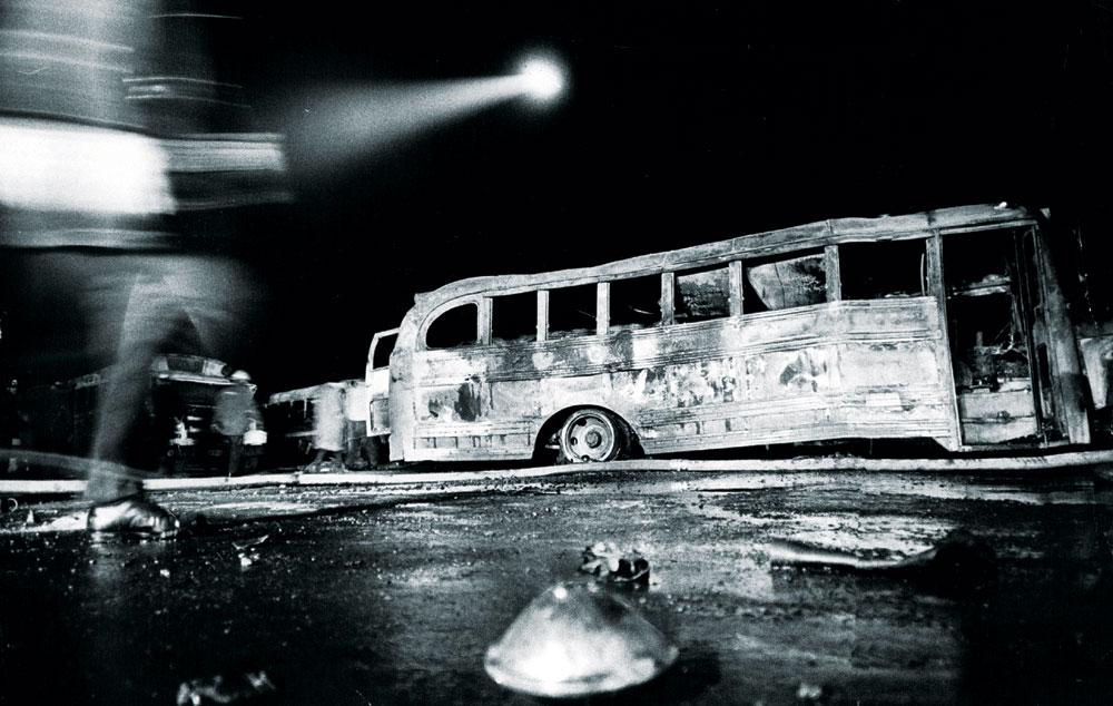 A light from a police helicopter shines down on some of the 38 fire-bombed buses at the DPS bus facility at 6th Ave and Federal on February 6, 1970. No one was ever charged with the crime. Photo by Steve Larson—Denver Post file photo