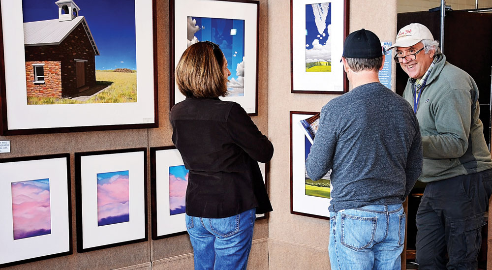 Visitors view paintings at the 2015 Cherry Arts Festival at Stanley. —Photo by Liz Levy for Cherry Creek Arts Festival