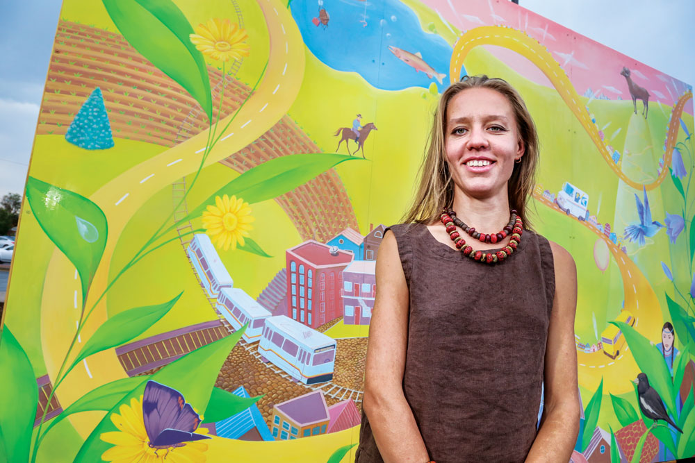 Artist Yulia Avgustinovich is pictured with a recent mural she created in Lakewood. She will be painting a street mural on Sept. 10 and 11 on Clinton St. in Aurora to create a grand entry to the Stanley Marketplace, including the Cherry Arts Festival the following weekend. The public is invited to participate in the painting project. RSVP to sign up for a volunteer shift.