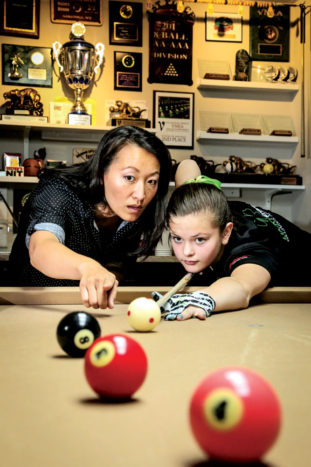 Leaving her demanding job as a pool room manager has allowed Samm Diep-Vidal, left, the opportunity to teach talented junior pool players, like Amanda Campbell, 13, while raising her daughters and selling billiards tables and equipment from her north Stapleton home.