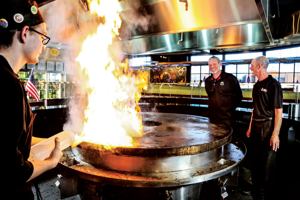 Area Director Eric Gray (left) and General Manager Chris Barkofske laugh as a Grill Warrior purposely makes huge flames that delight customers. 