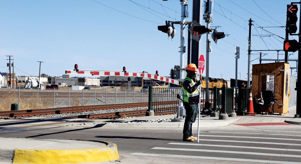 A flagger stands at the Ulster St. crossing on the A Line, one of the worst performing intersections in the corridor on timing.