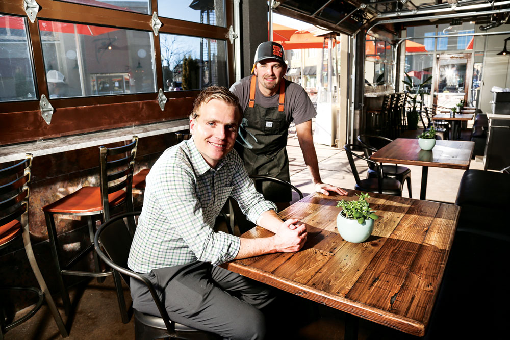Chop Shop owners Christian Anderson and Clint Wangsnes are shown in a patio area of the restaurant with garage doors that open in warm weather.