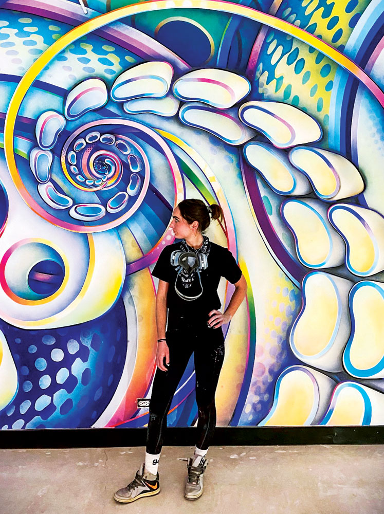 Denver artist Anna Charney stands in front of one of her completed murals.