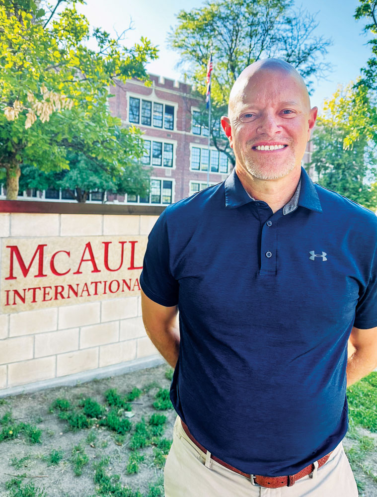 Brian Duwe, PhD, the new principal of McAuliffe International School, stands in front of the school building.