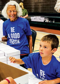 Marcia Praver and her 7-year-old grandson help fill boxes with supplies for teachers. 