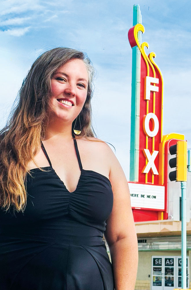 Aurora Cultural Arts District president Morgan Schreiber in front of the newly refurbished Aurora Fox Arts Center sign.